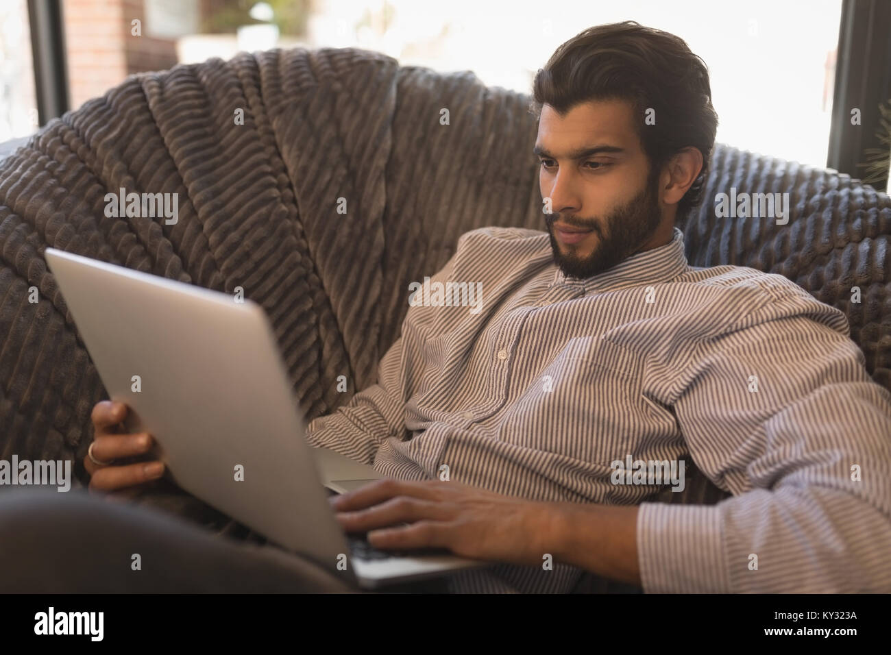 Man using laptop while relaxing on arm chair Stock Photo