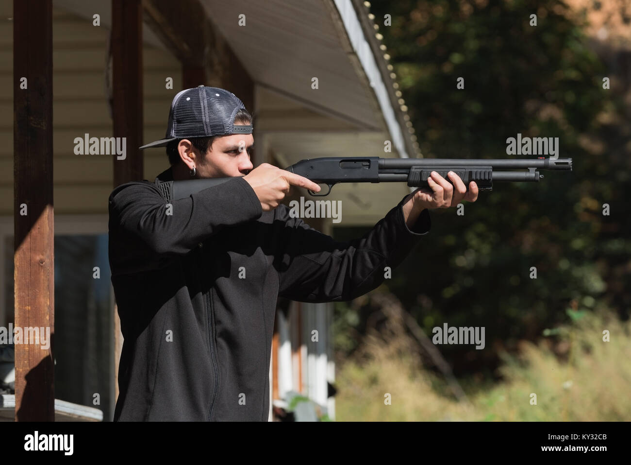 Man aiming shotgun at target in shooting range Stock Photo