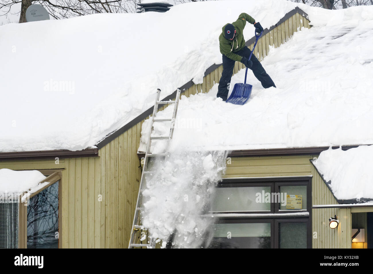 A man clearing snow from the roof of a house, Quebec City in winter Stock Photo