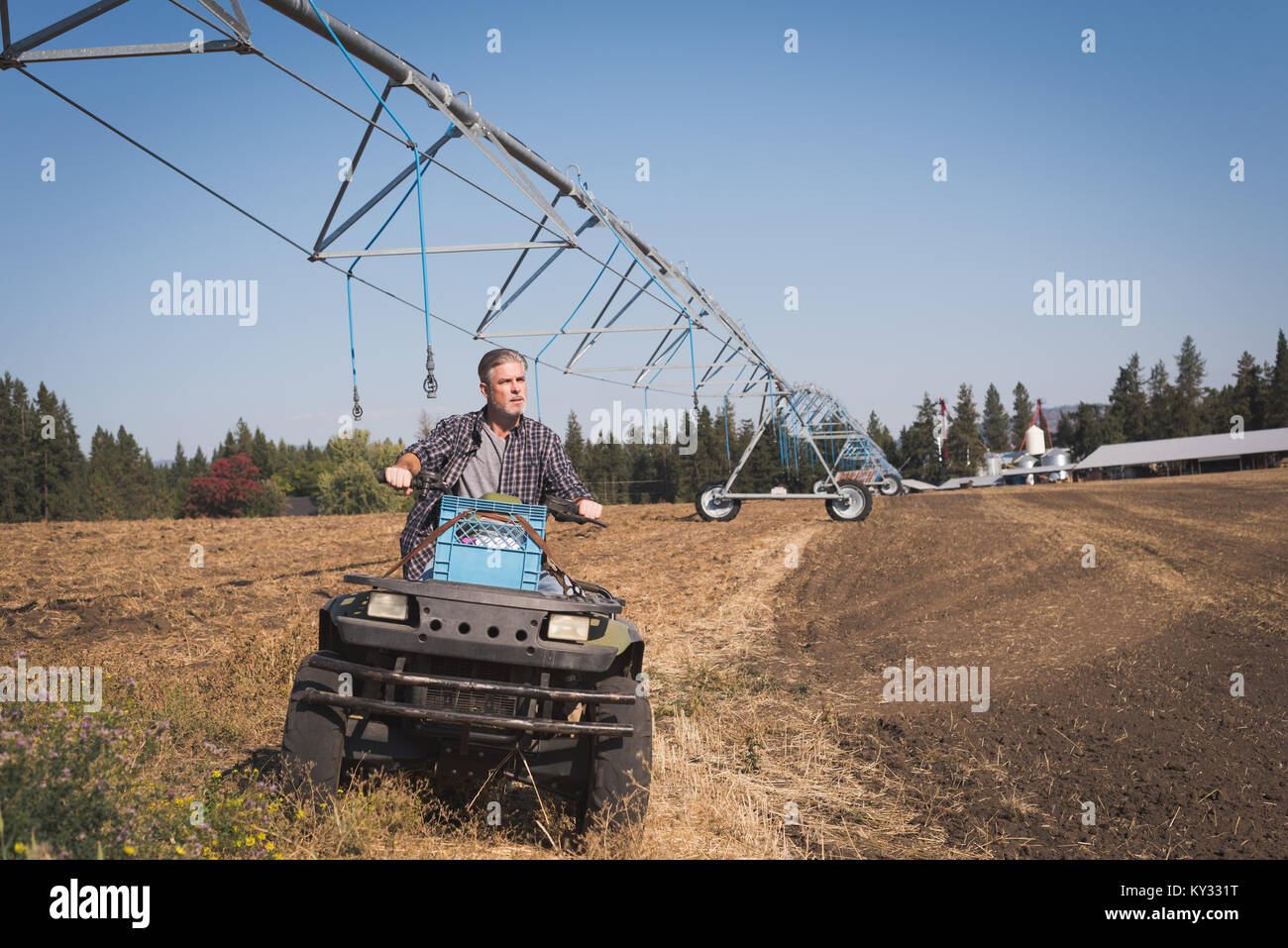 Farmer driving land vehicle in field Stock Photo