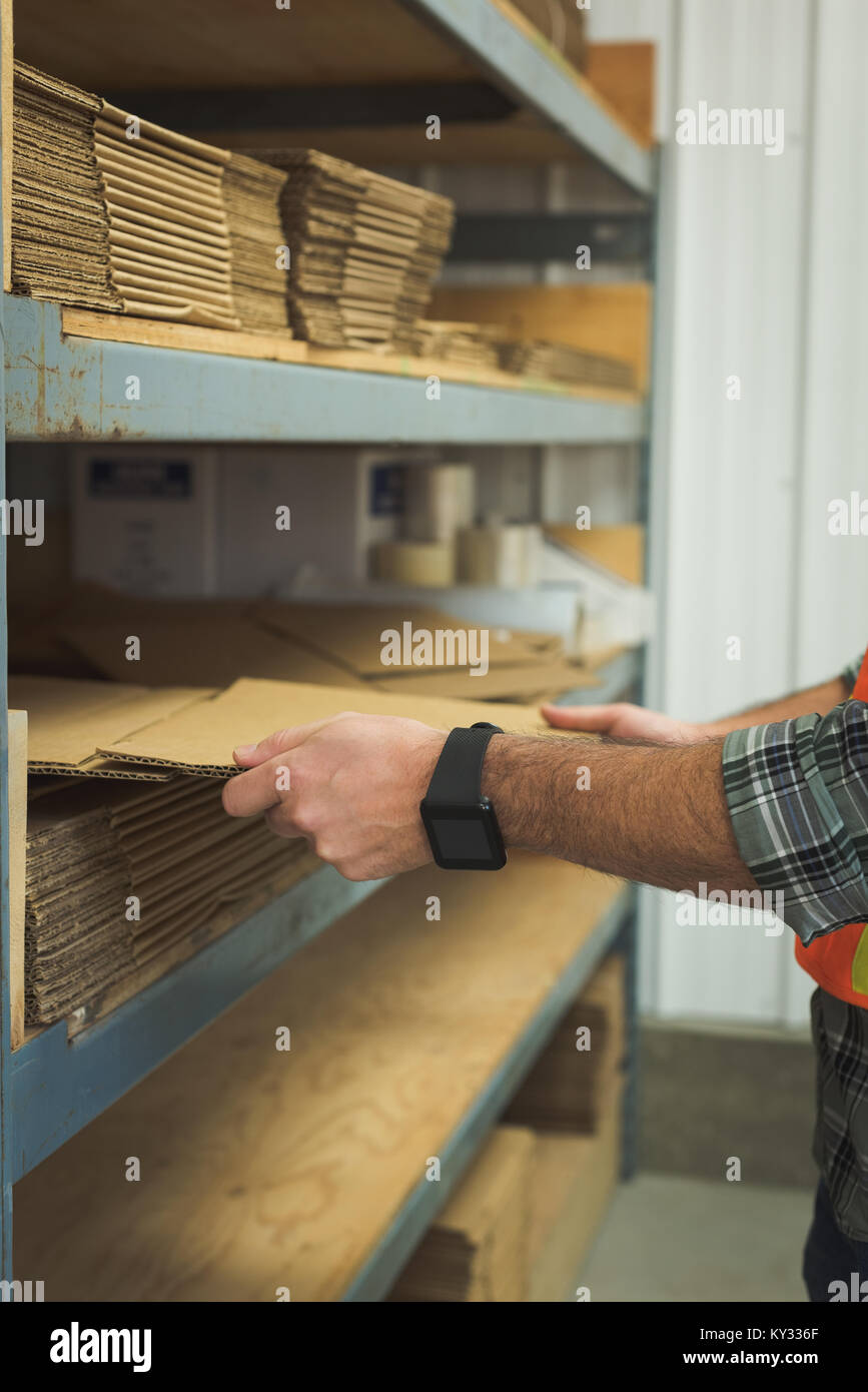Man arranging cardboard in shelf Stock Photo - Alamy