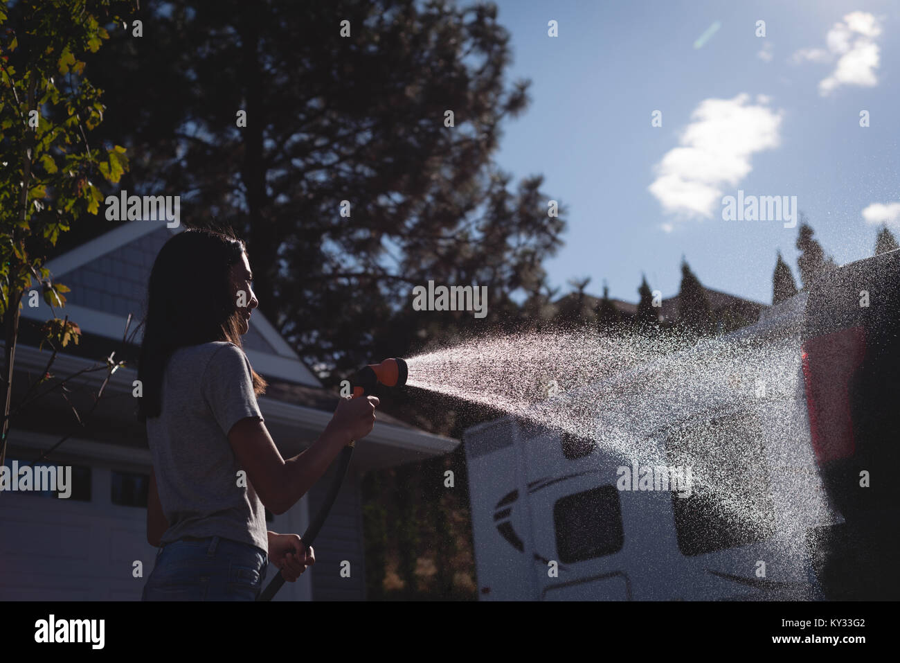 Woman washing her car with a high pressure water jet Stock Photo
