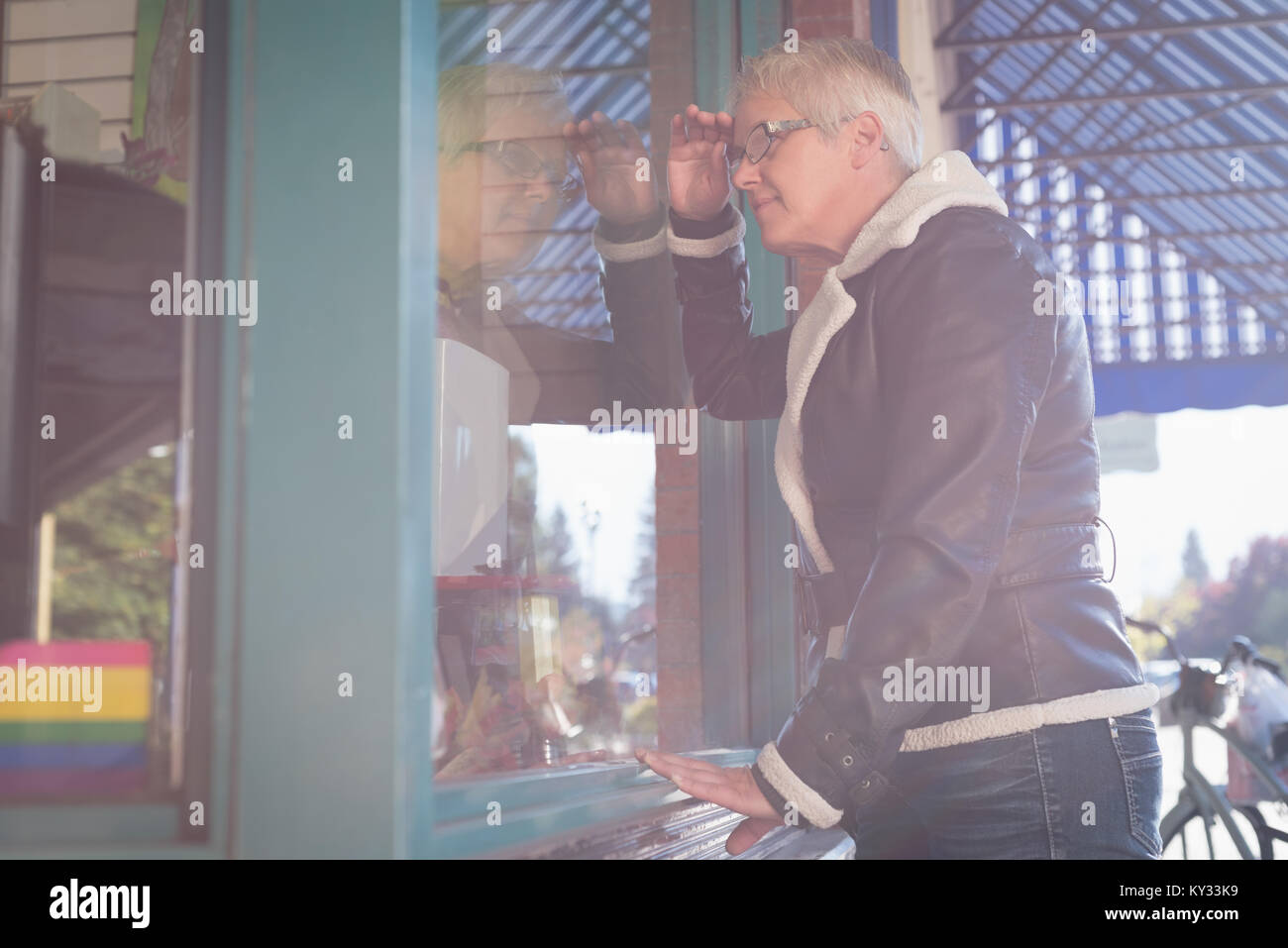 Senior woman peeping through the glass window Stock Photo