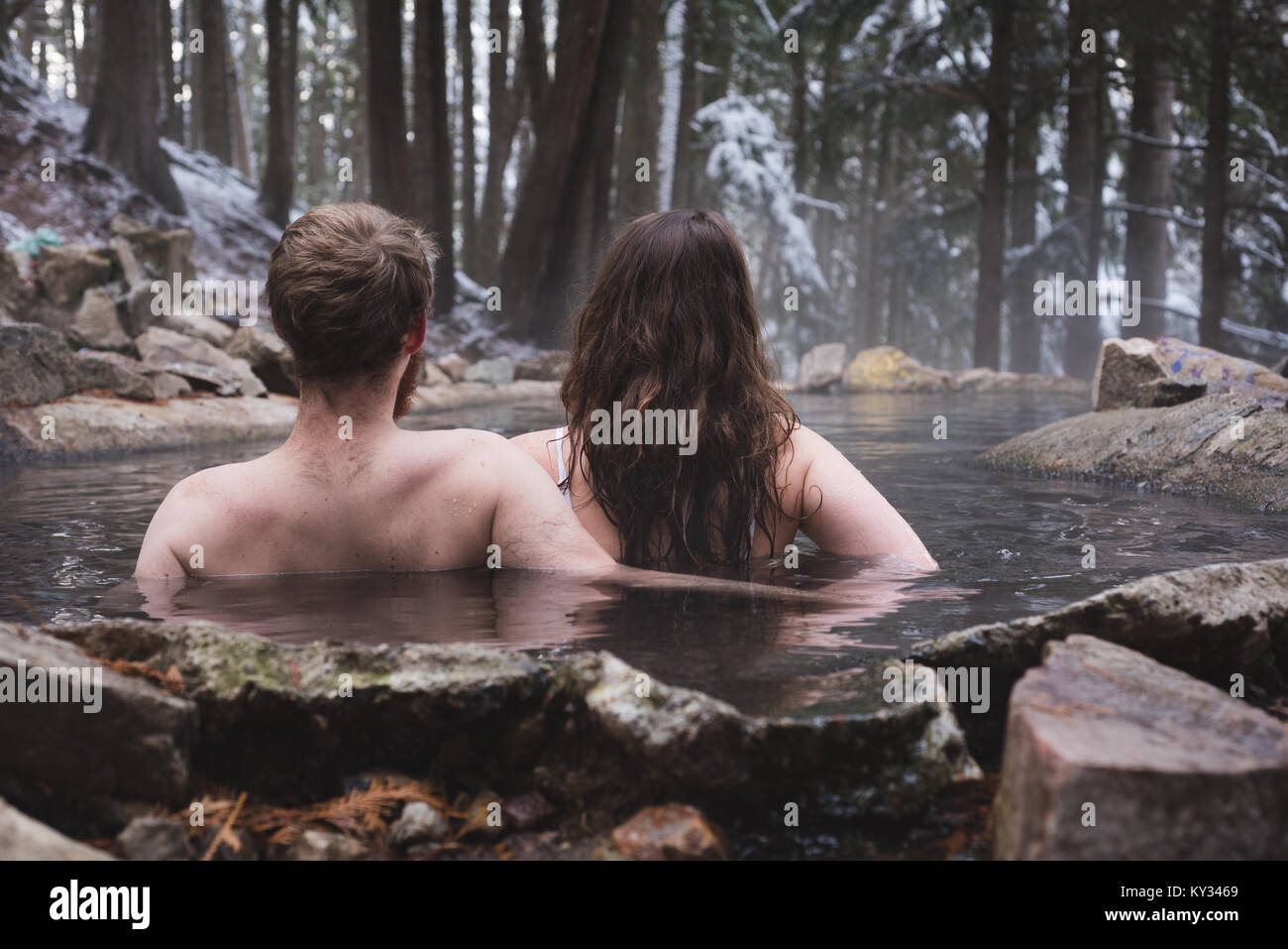 Rear view of couple relaxing in hot spring Stock Photo