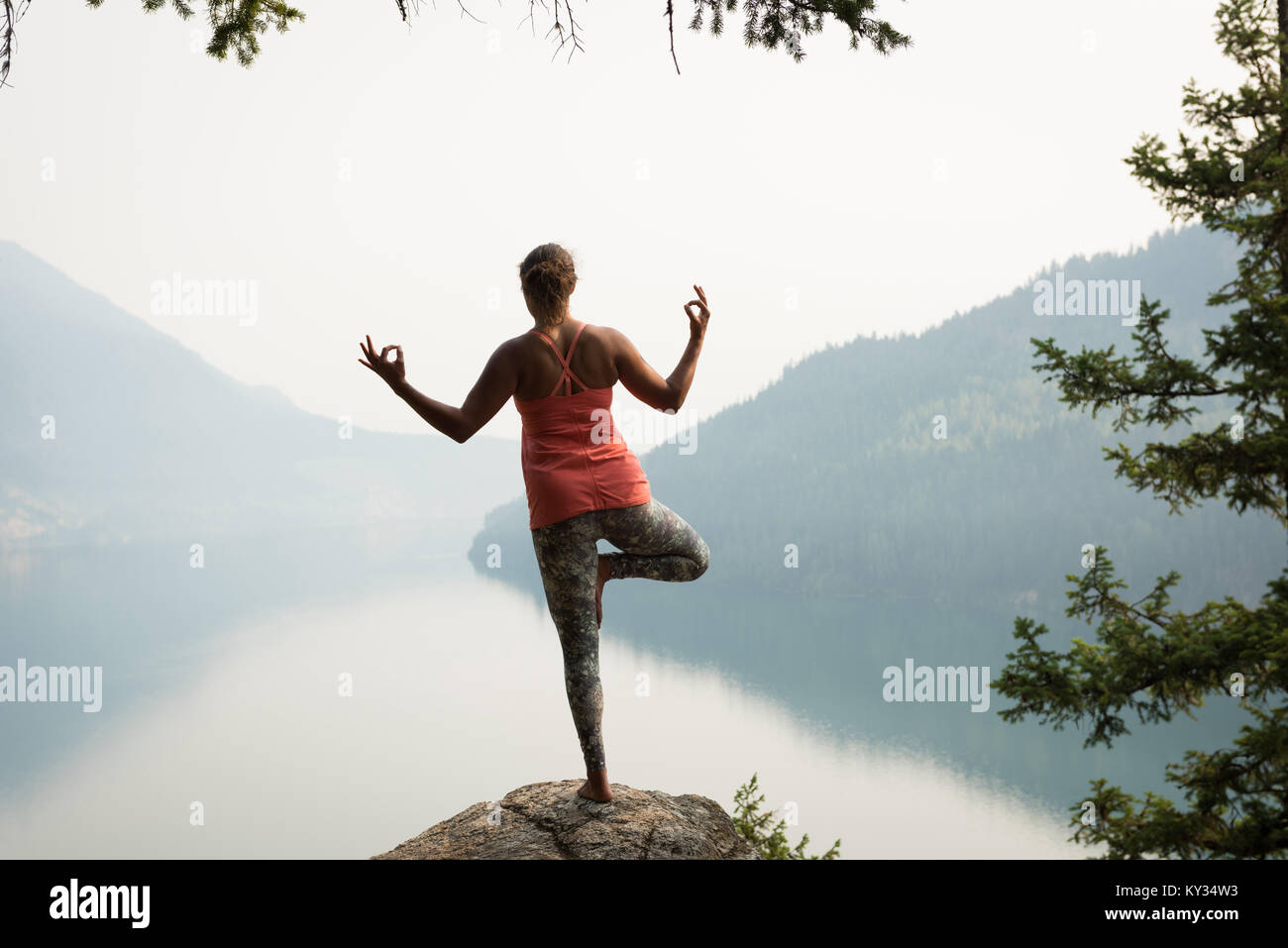 Fit woman balancing on one leg on the edge of a rock Stock Photo