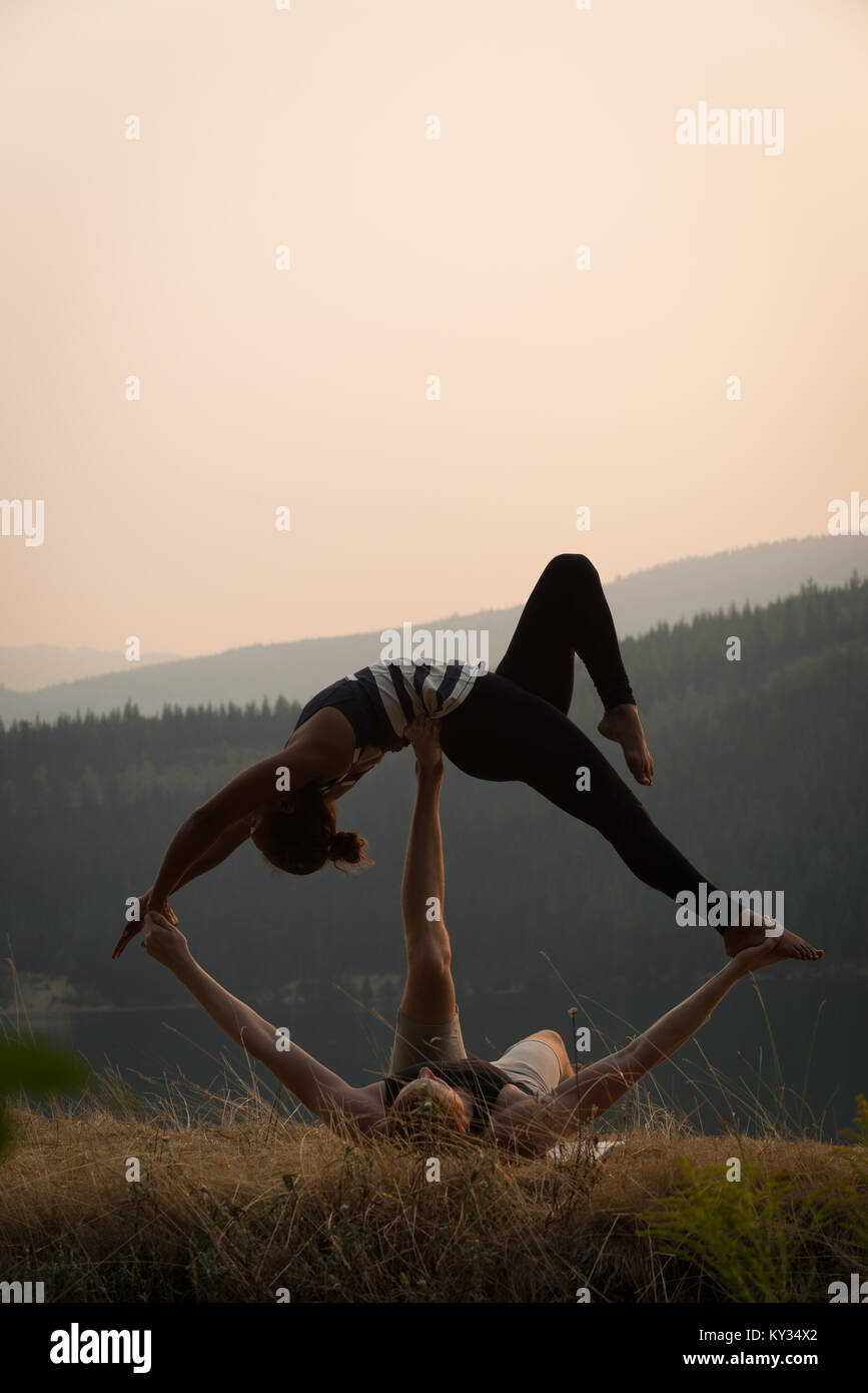 Sporty couple practicing acro yoga in a lush green ground Stock Photo
