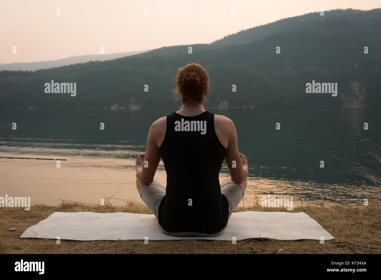 Fit woman sitting in meditating posture on an open ground Stock Photo