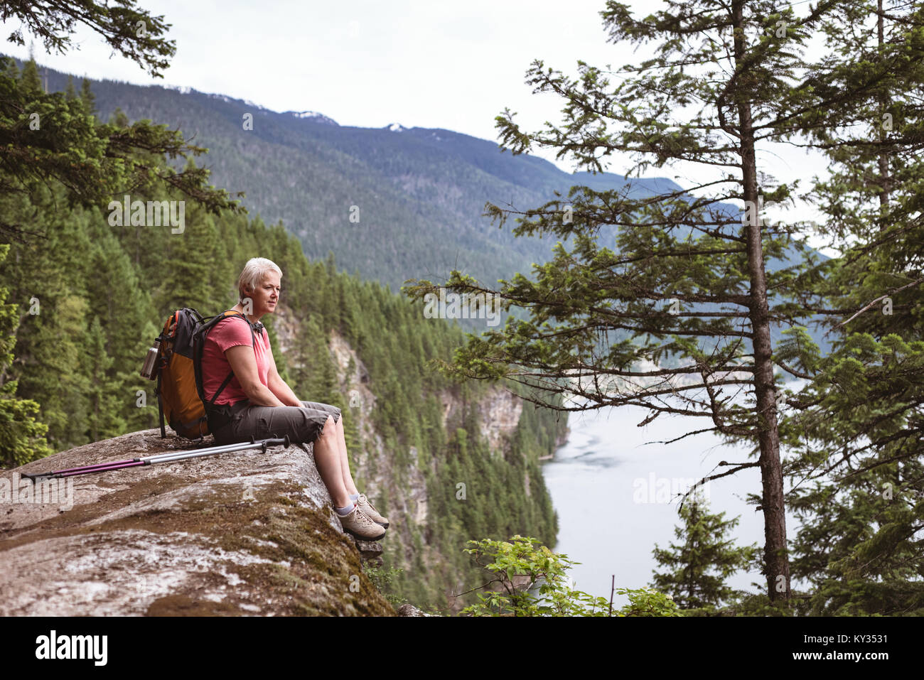 Mature woman relaxing on rock and looking at view Stock Photo