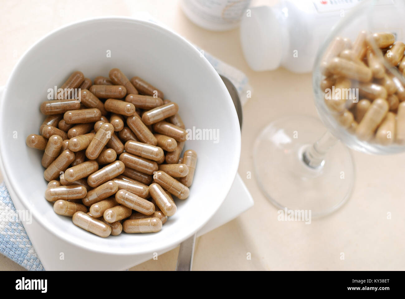 Medicine capsules in soup bowl with glass of capsules in background. Signifying drug addiction, healthy eating and lifestyle, dieting and slimming, an Stock Photo