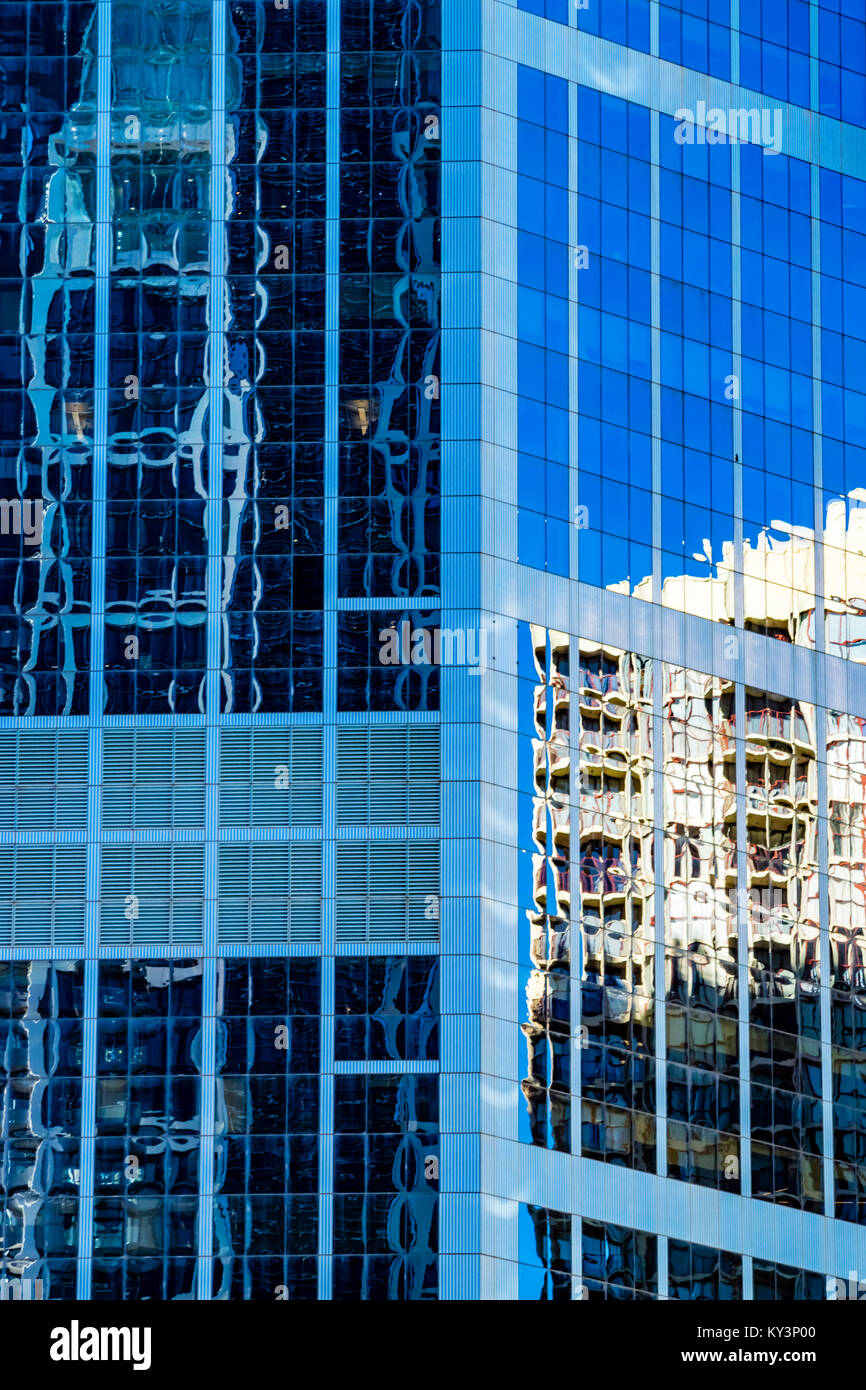 Modern architecture concept, skyscraper reflections in high rise building. Abstract highrise office buildings reflecting in blue glass facade. Stock Photo