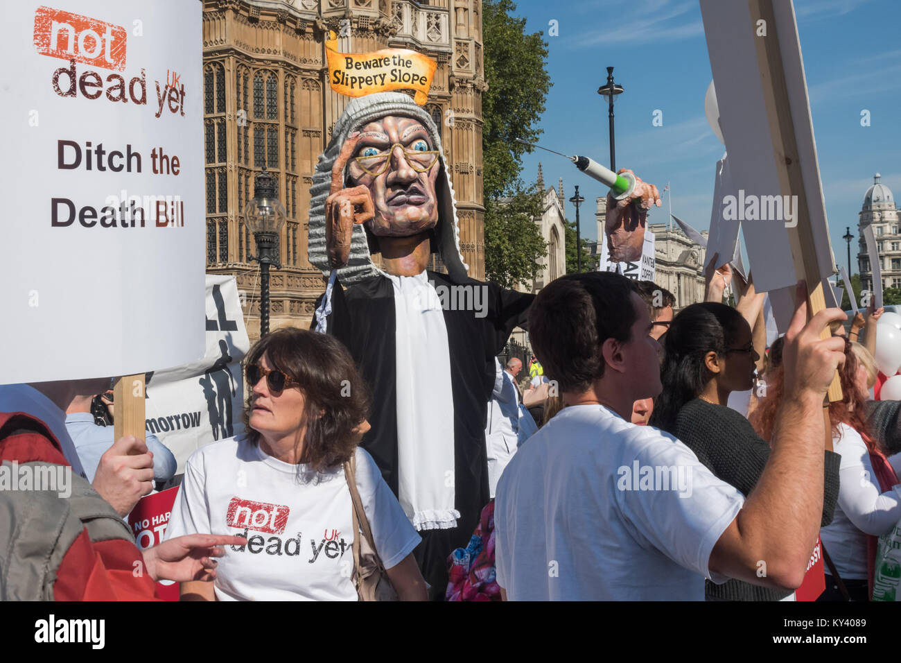Protesters in Old Palace Yard calling for a NO vote on the Assisted Suicide Bill being debated in Parliament had brought a giant puppet judge with a syringe and the message 'Beware the Slippery Slope'. Stock Photo