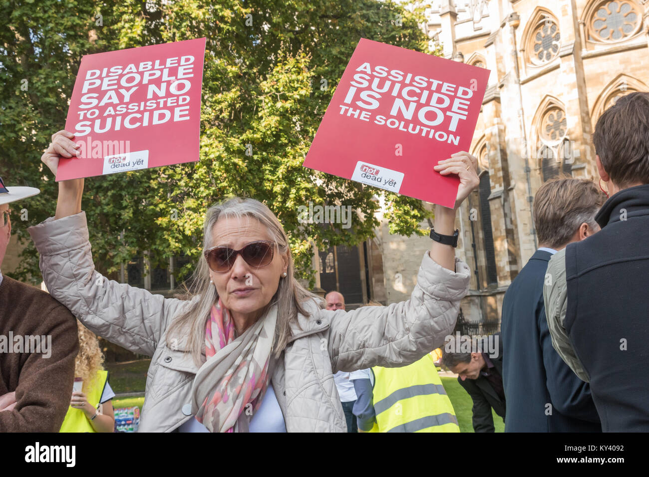 A woman holds up two posters against the Assisted Suicide Bill at the protest in Old Palace Yard as Assisted Suicide Bill is debated in Parliament Stock Photo