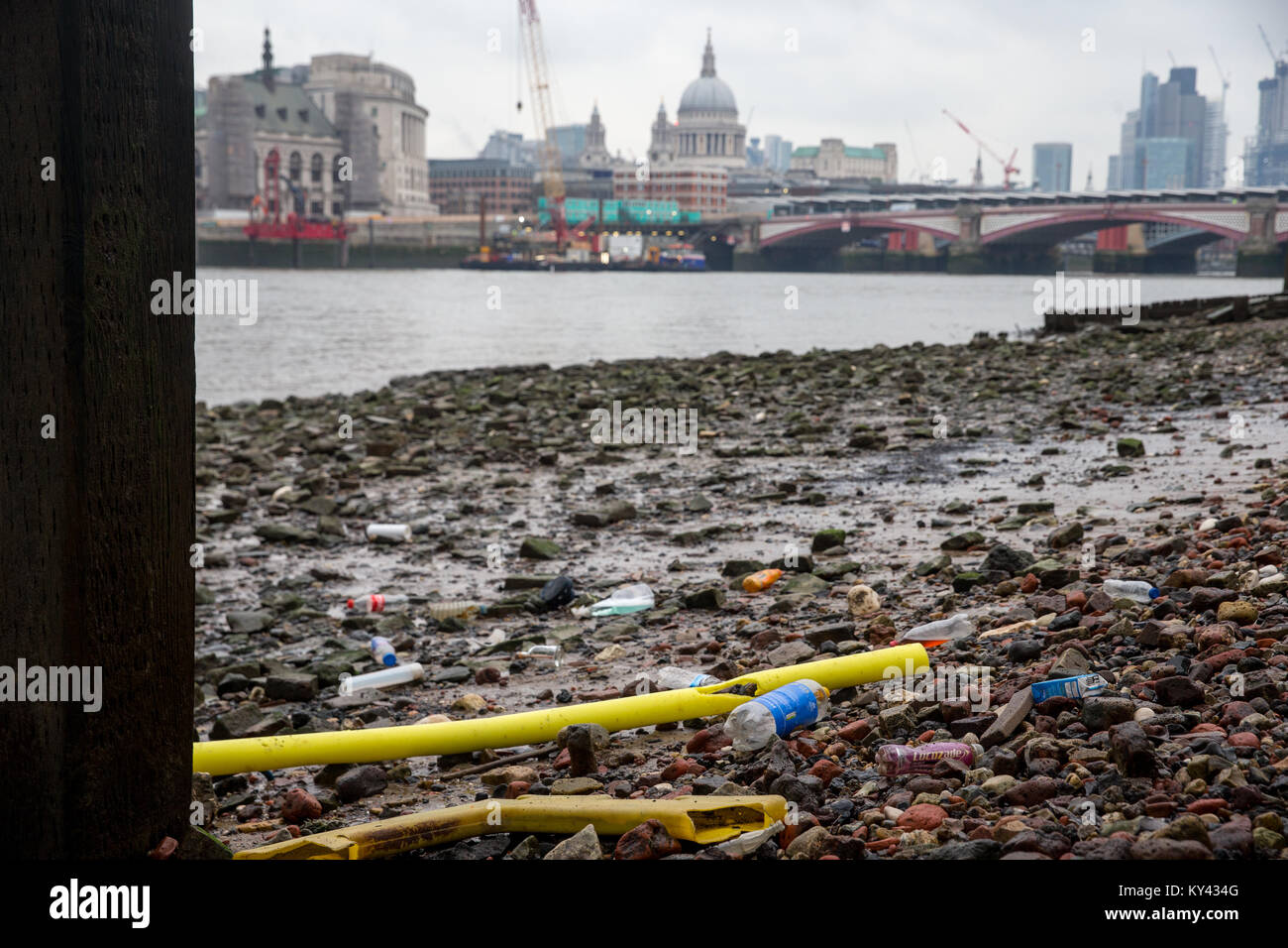 Plastic rubbish and bottles on the banks of the River Thames at low tide with St Pauls and the City of London in the background Stock Photo
