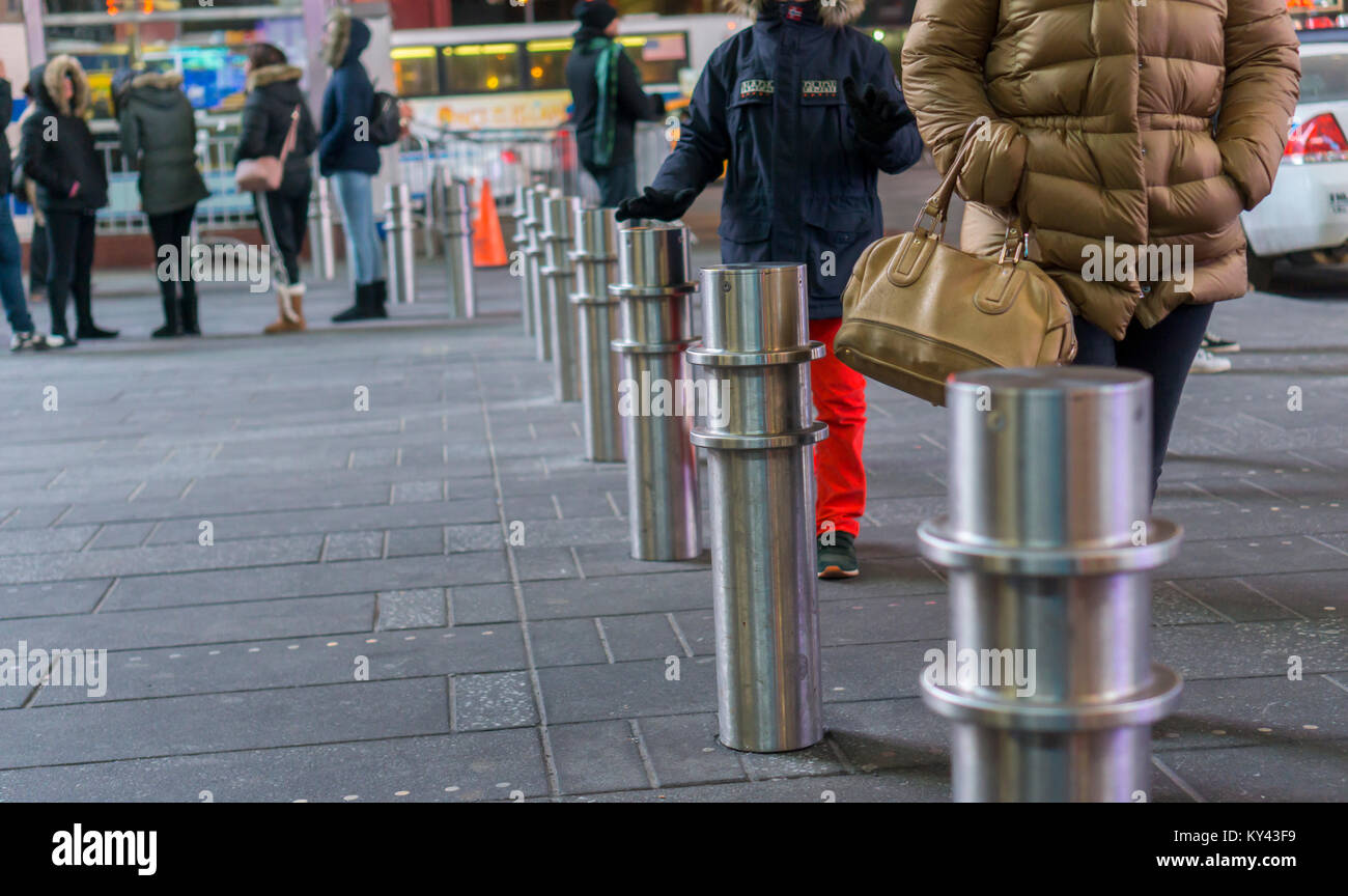 Visitors to Times Square in New York on Tuesday, January 3, 2018 pass between security bollards preventing vehicles from driving into pedestrian spaces. New York Mayor Bill De Blasio announced that the city will be installing 1500 bollards at various locations around the city as a preventative security measure at a cost of $50 million. In some cases the bollards will replace the concrete block 'sugar cubes' that were an impediment to pedestrian traffic and in other cases they will be in new locations. (Â© Richard B. Levine) Stock Photo