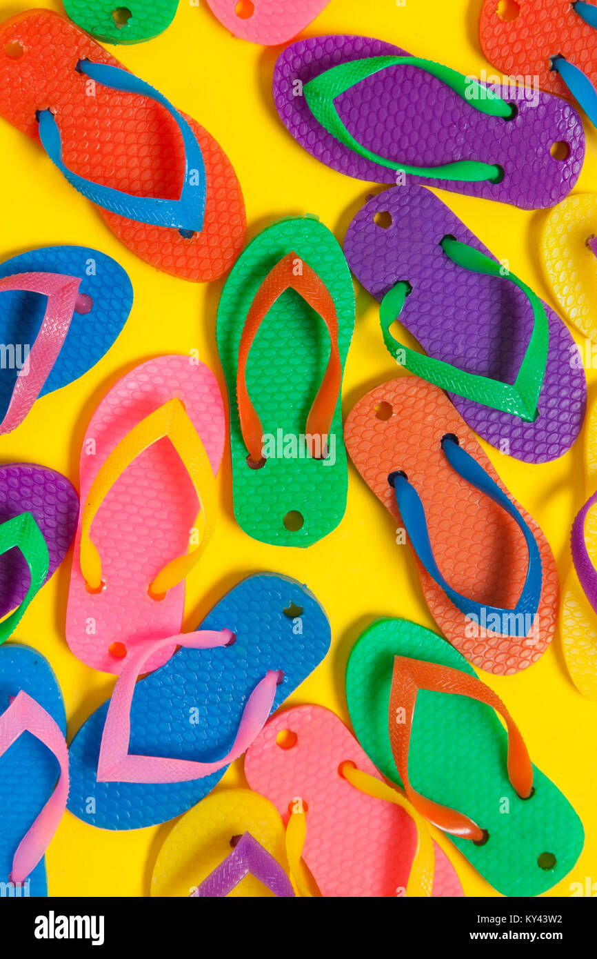 collection of colourful summer flip flop sandals on a bright yellow ...