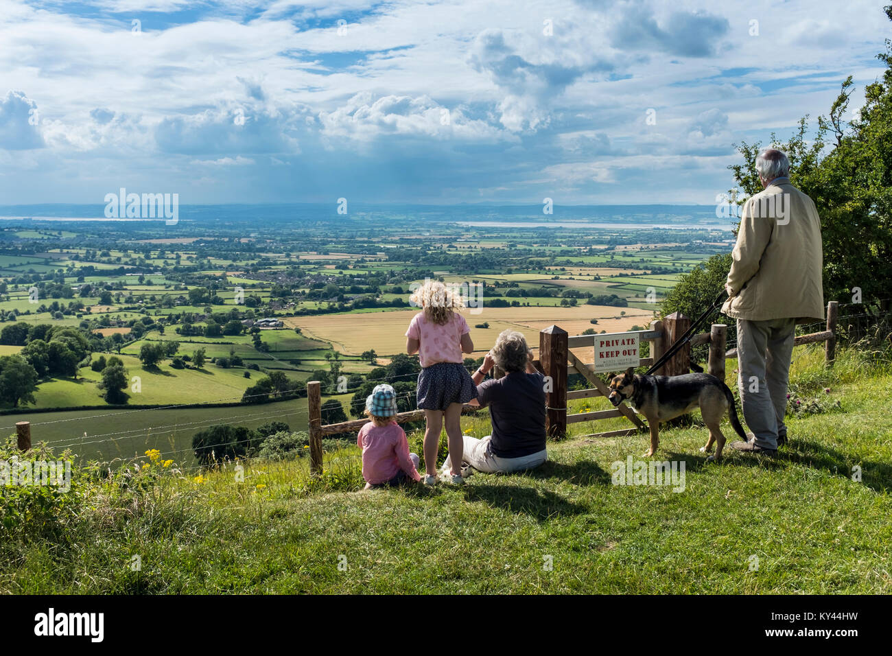 Elderly couple with young grandchildren and a dog enjoying panoramic views from Coaley Peak picnic site and Viewpoint, Dursley, Gloucestershire, UK Stock Photo