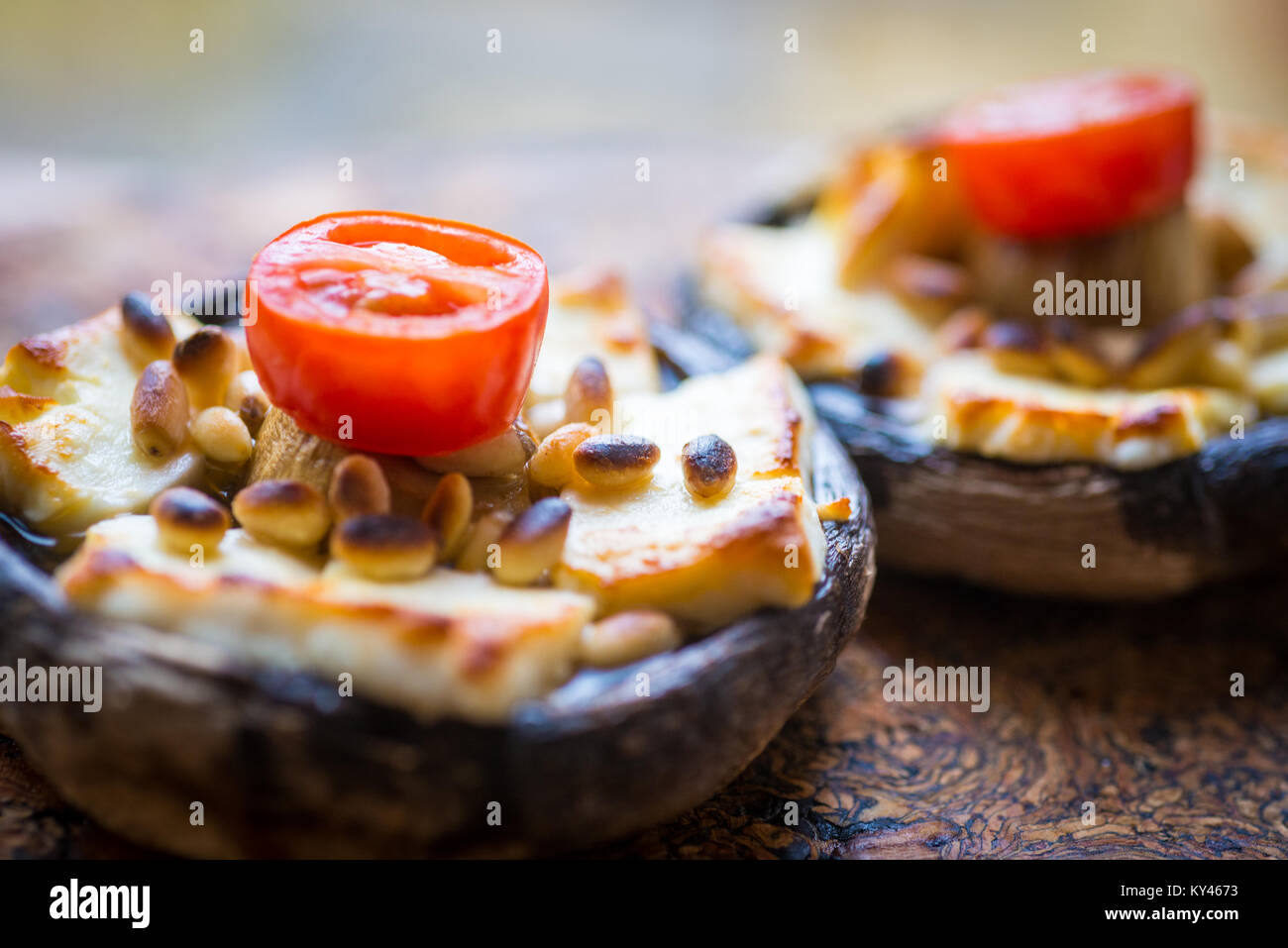Tomato, halloumi cheese and pine nuts grilled on an inverted mushroom. Stock Photo