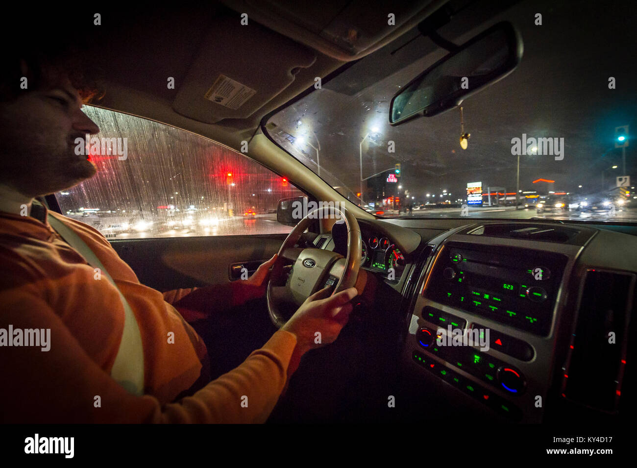Young man driving a car at night - view inside the cabin Stock Photo