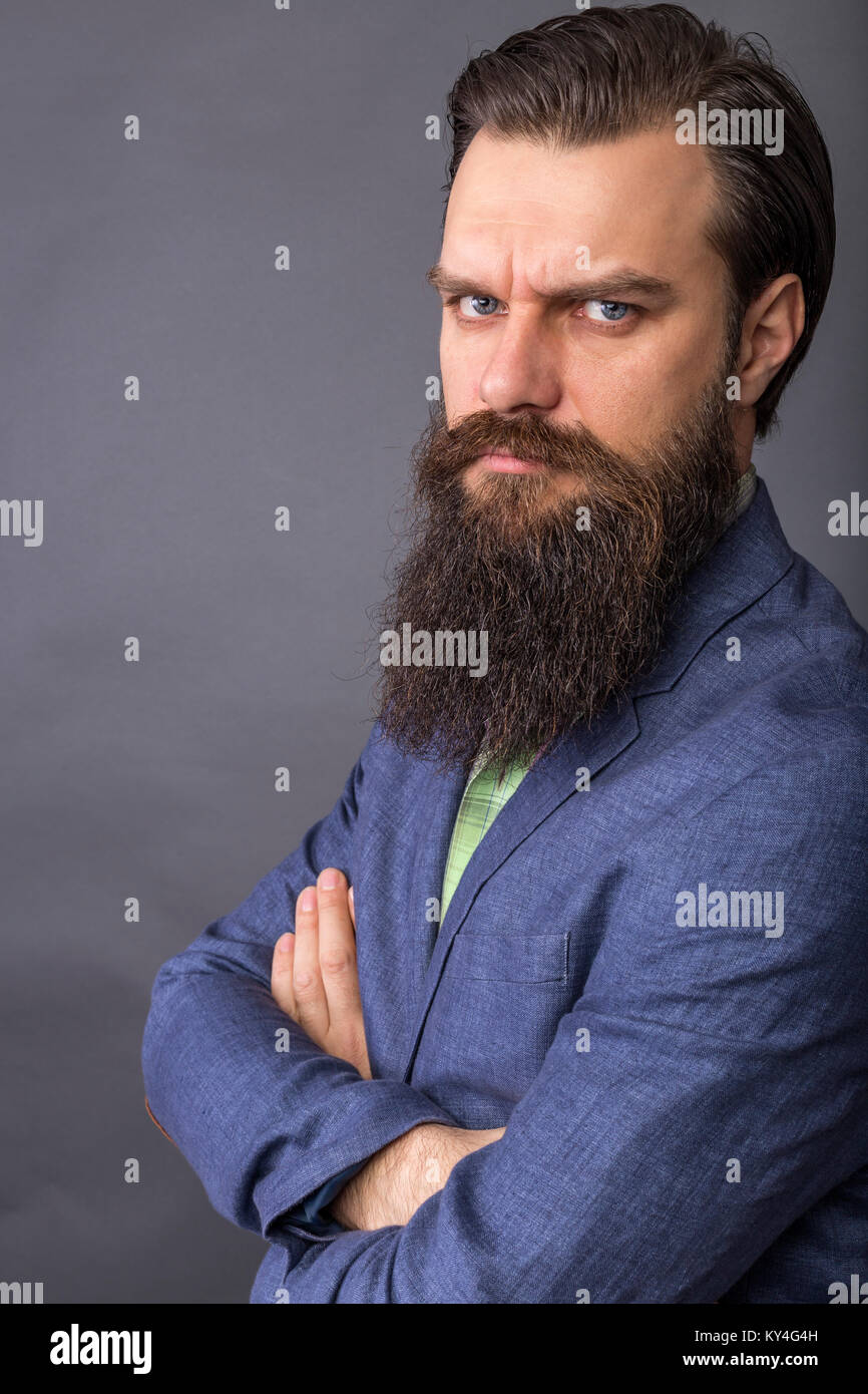 Studio shot of a young angry man with beard and mustache.Gray ...