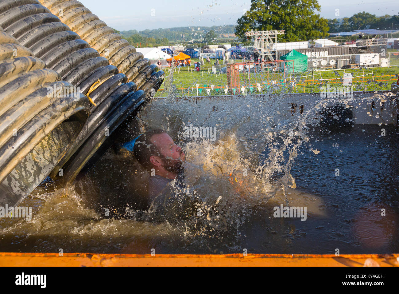 Sussex, UK. A male competitor closes his eyes as he splashes into a large pool of freezing cold water during a Tough Mudder event. Stock Photo