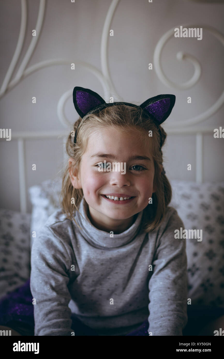 Portrait of smiling girl sitting on bed Stock Photo - Alamy