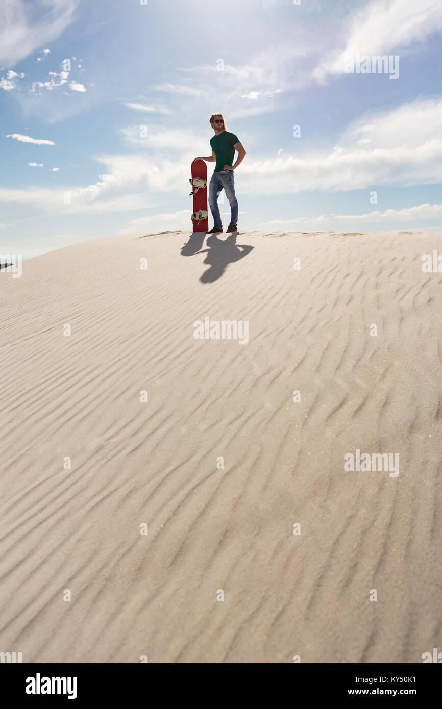 Man with sandboard standing in the desert Stock Photo