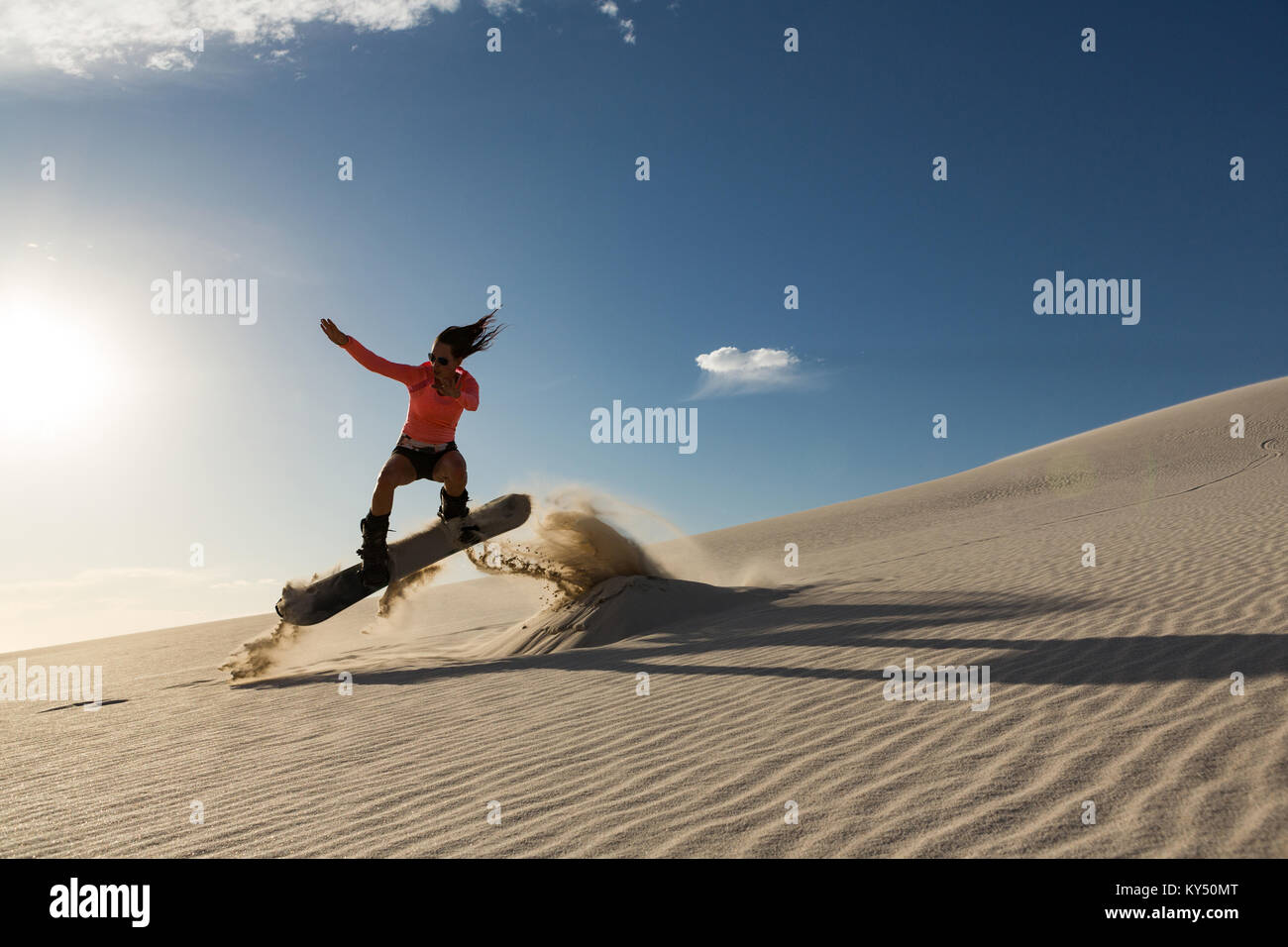 Man sandboarding on sand dune Stock Photo
