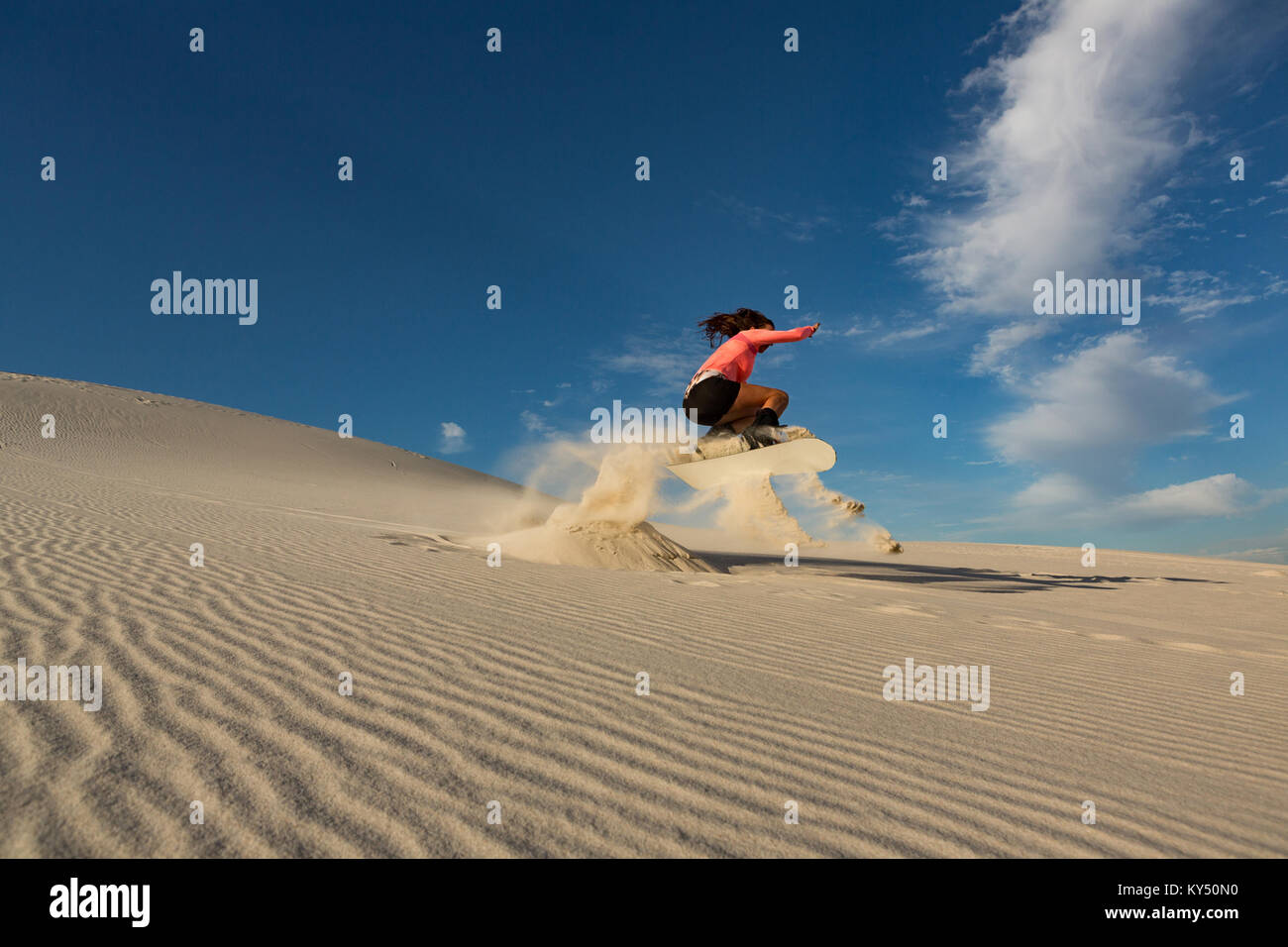 Woman sandboarding on sand dune Stock Photo