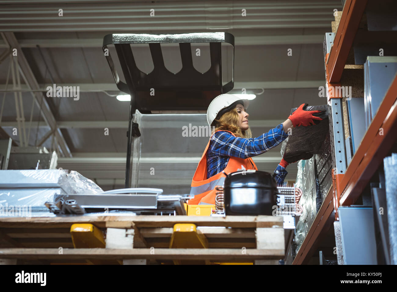 Female worker unloading machine part from rack Stock Photo
