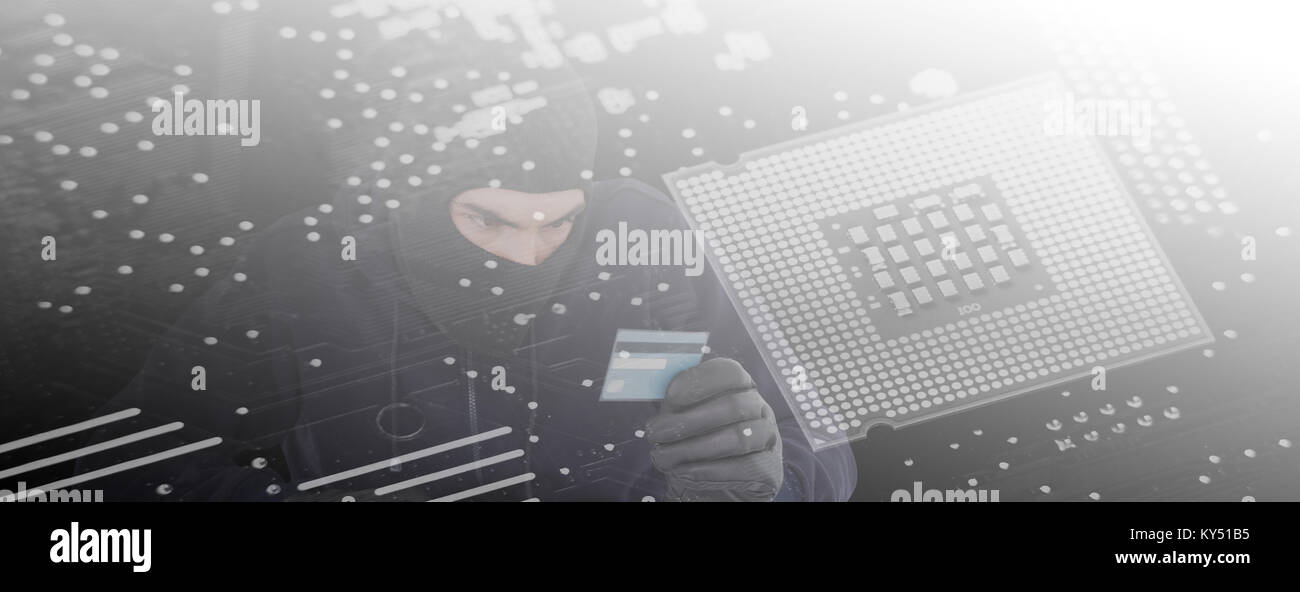 Composite image of focused burglar using computer and debit card Stock Photo