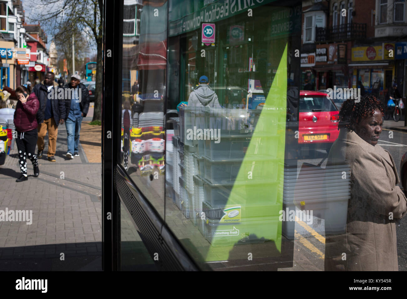 A woman standing at bus stop on Narborough Road, in the West End