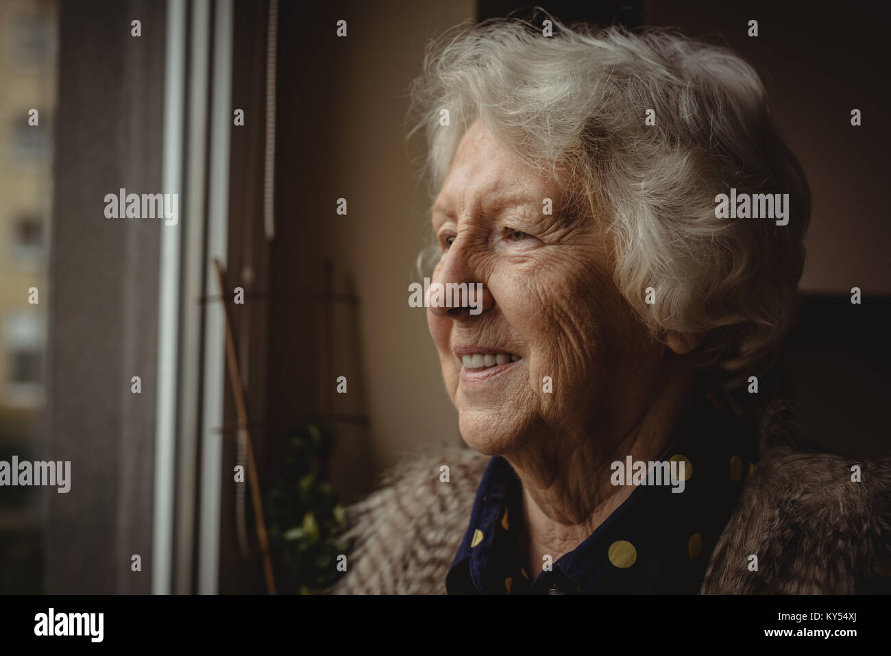 Smiling senior woman looking out of the window Stock Photo