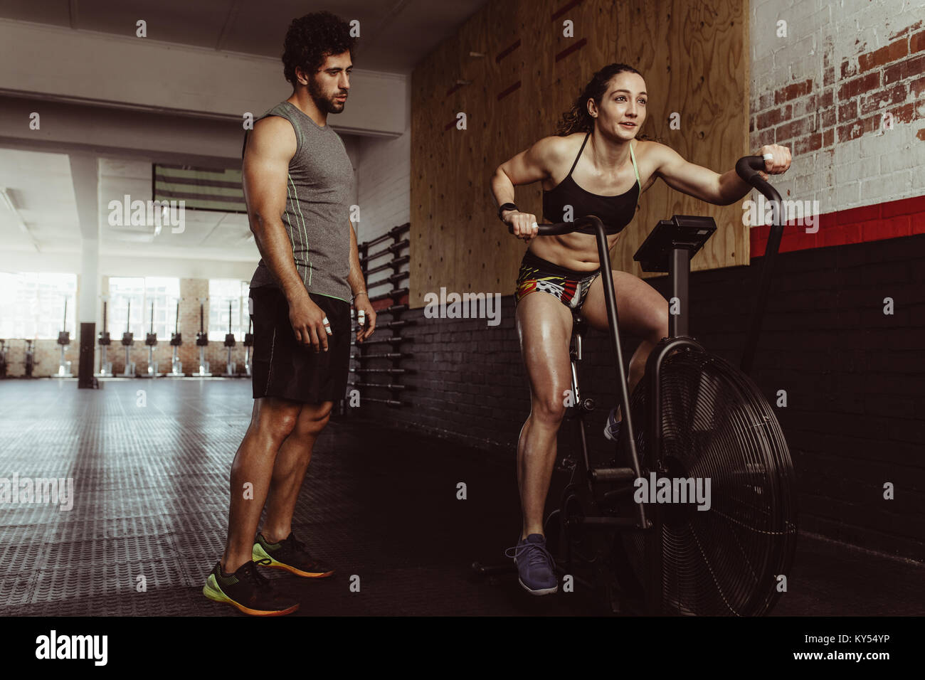 Fitness female using air bike for cardio workout at gym with personal Stock  Photo - Alamy