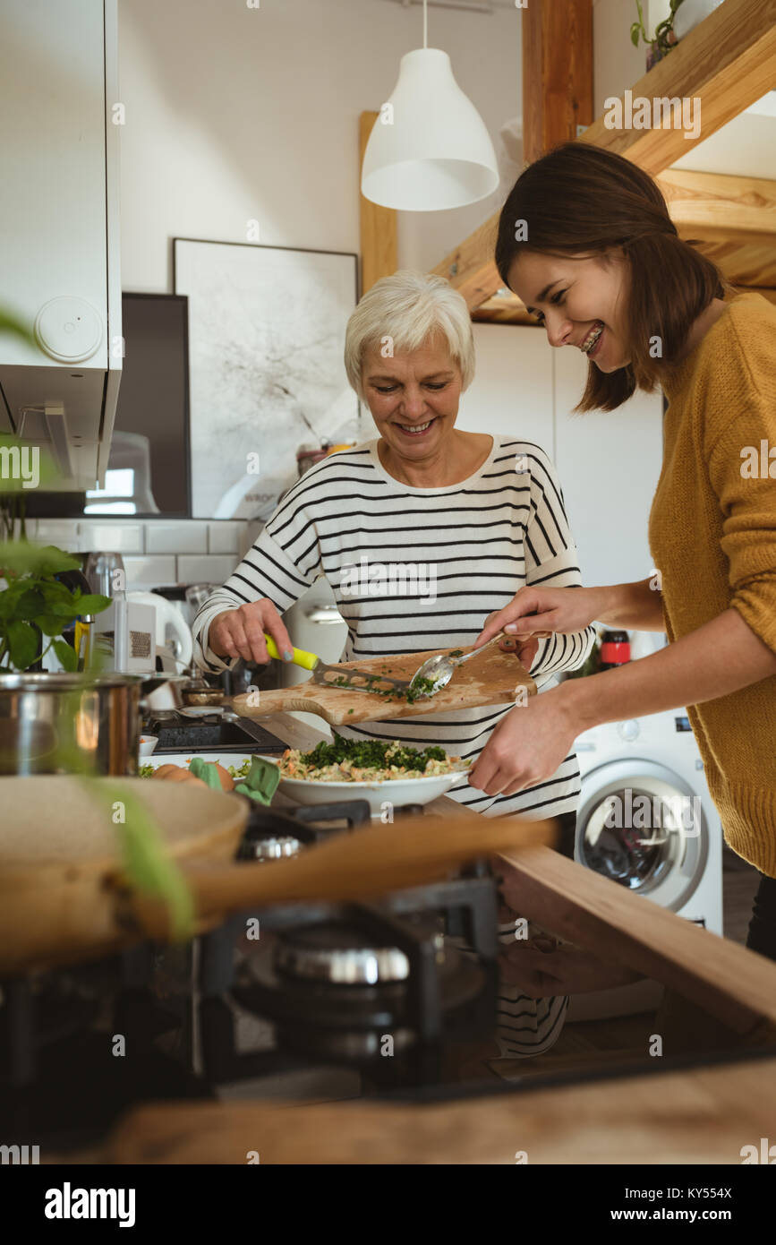 Smiling senior woman and daughter cooking together in the kitchen Stock Photo