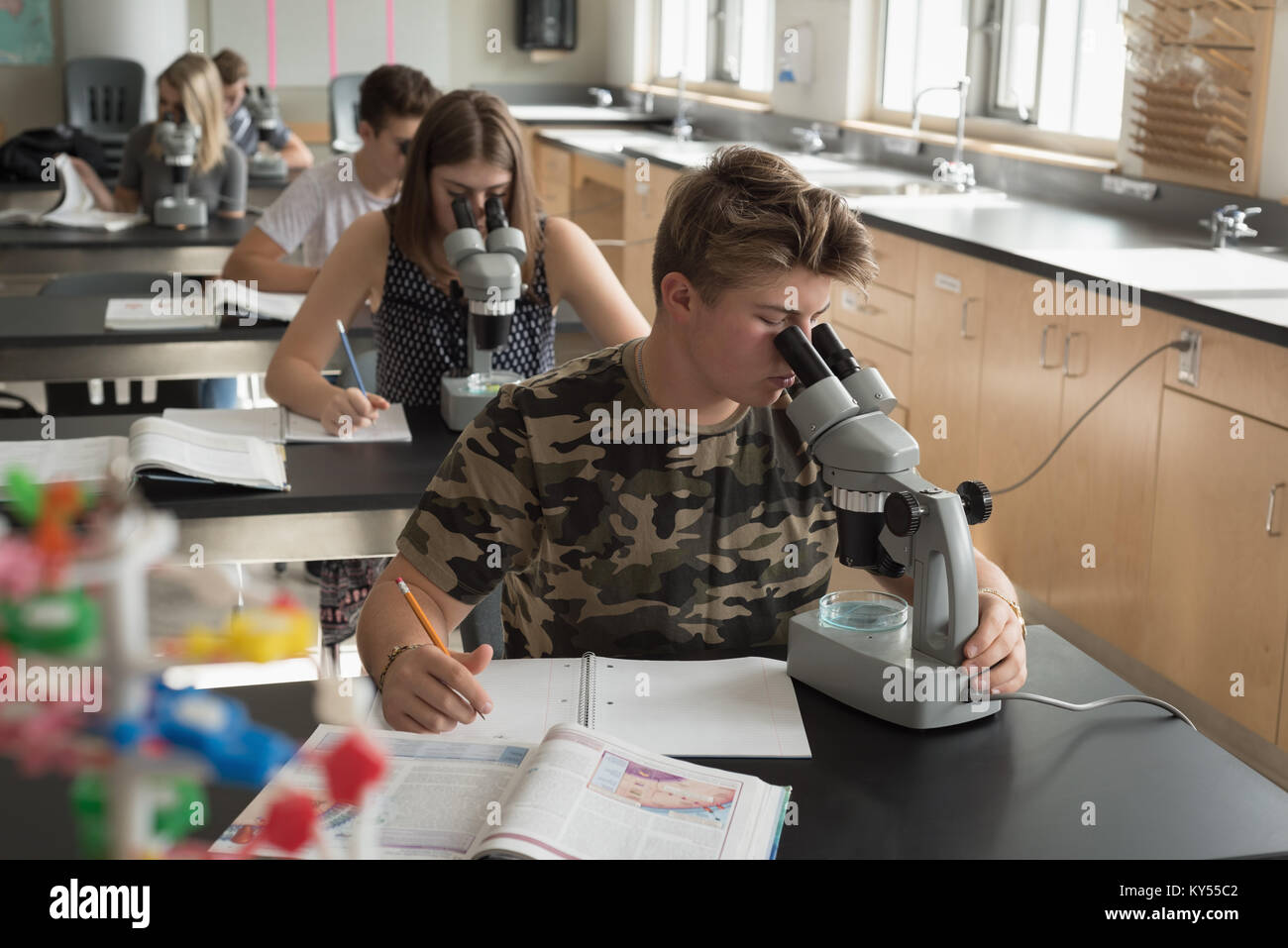 College students experimenting on microscope in laboratory Stock Photo