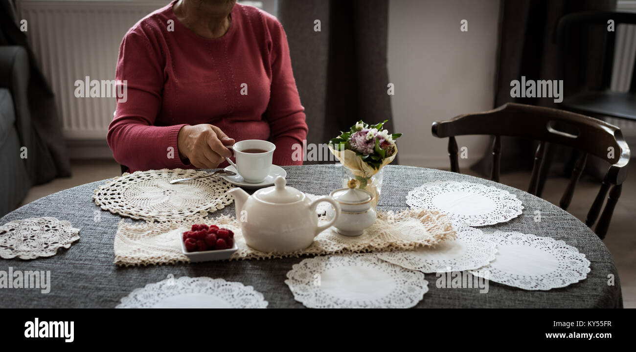 Senior woman having cup of tea in living room Stock Photo