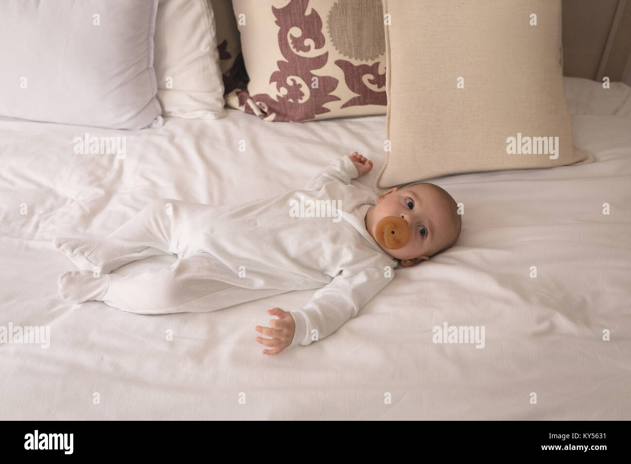 Cute little baby with pacifier in mouth sleeping on bed Stock Photo