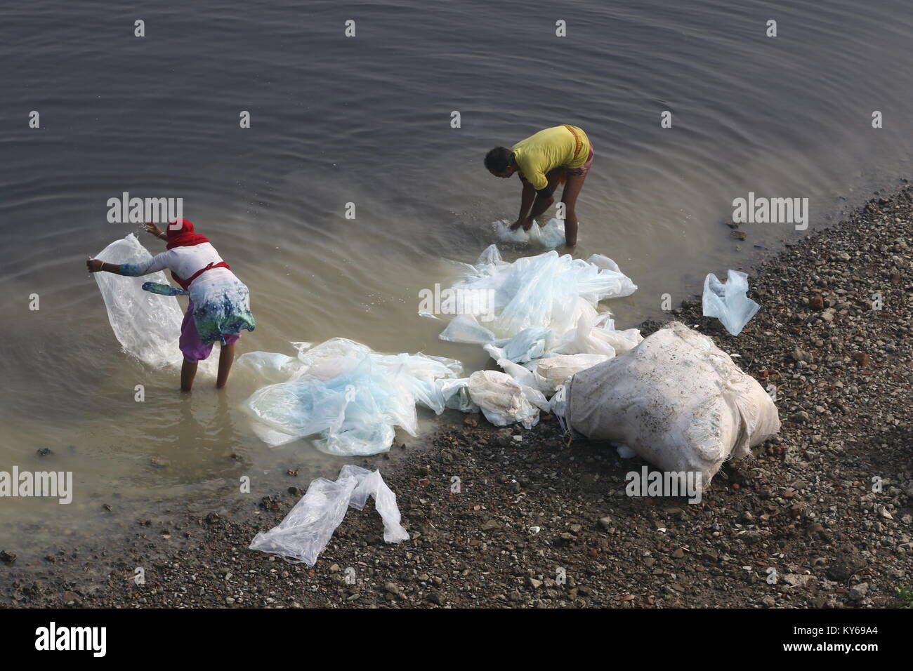 Workers wash plastic chemical bag in the polluted Buriganga River in