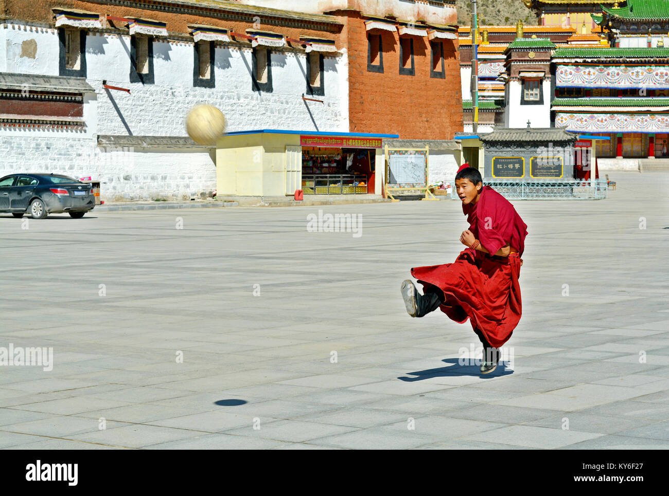 A Tibetan monk playing football in the courtyard of Labrang monastery in Xiahe, Gansu Province, China Stock Photo