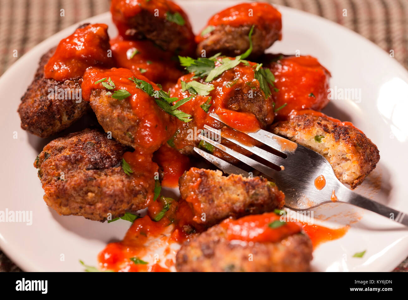 Eating fried meatballs made from pork and beef meat with tomato sauce and herbs on plate Stock Photo