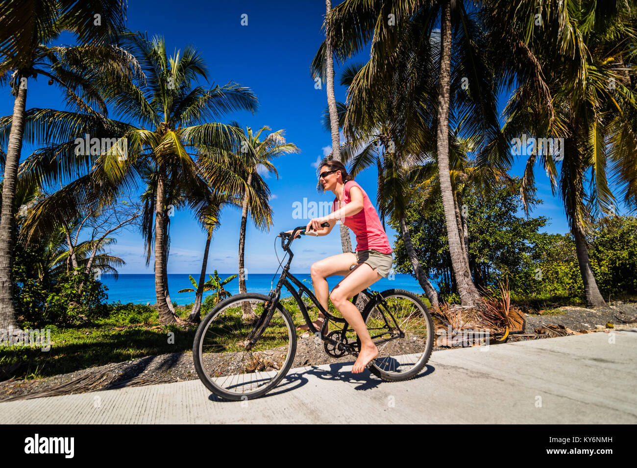 SAN ANDRES ISLAND, Colombia   Circa March 2017. Woman Bicycling Bare Foot in the Street in the Caribbean Stock Photo
