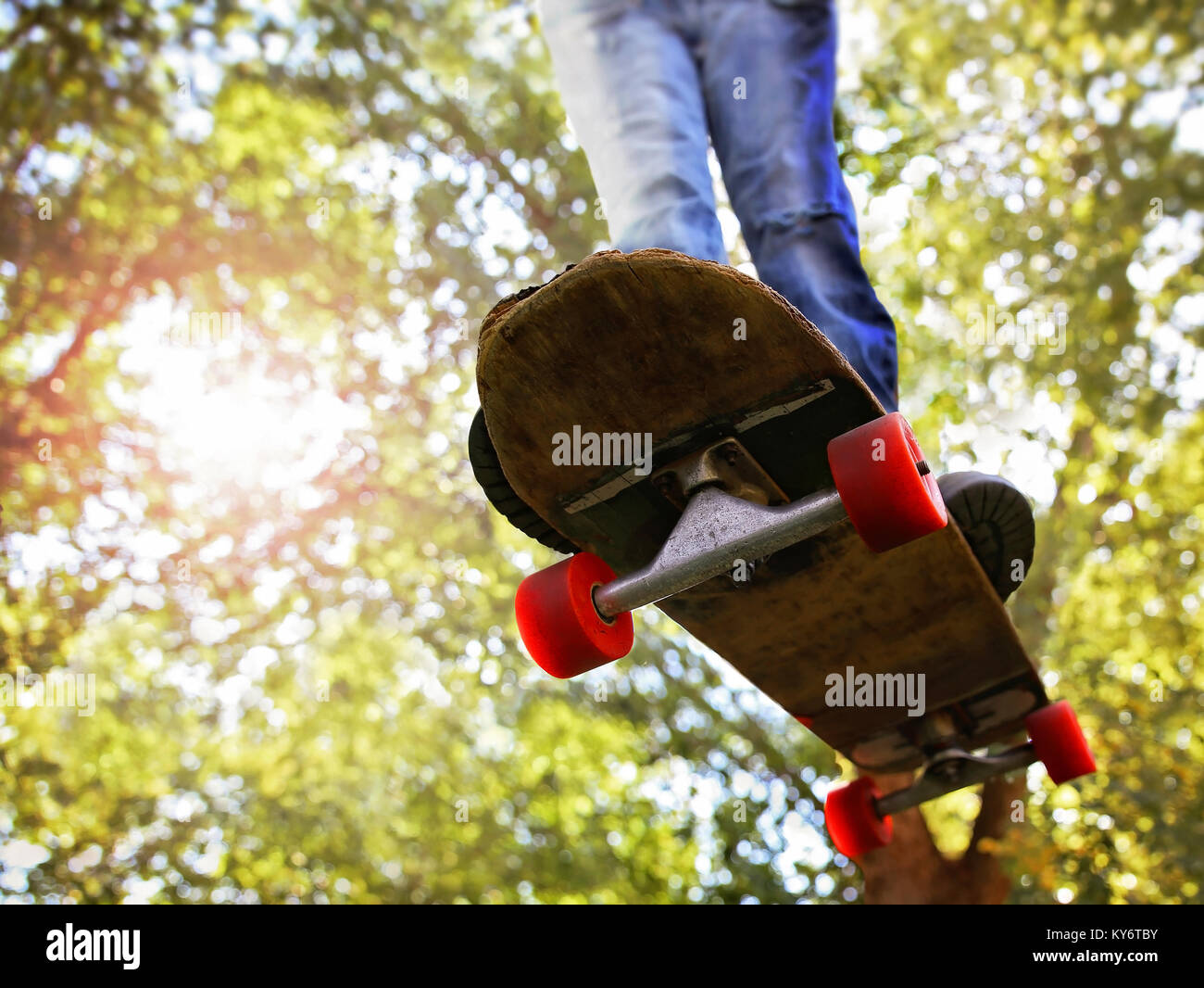 a wide angle shot of a skateboarder jumping trees in the background toned with a retro vintage instagram filter app or action effect Stock Photo