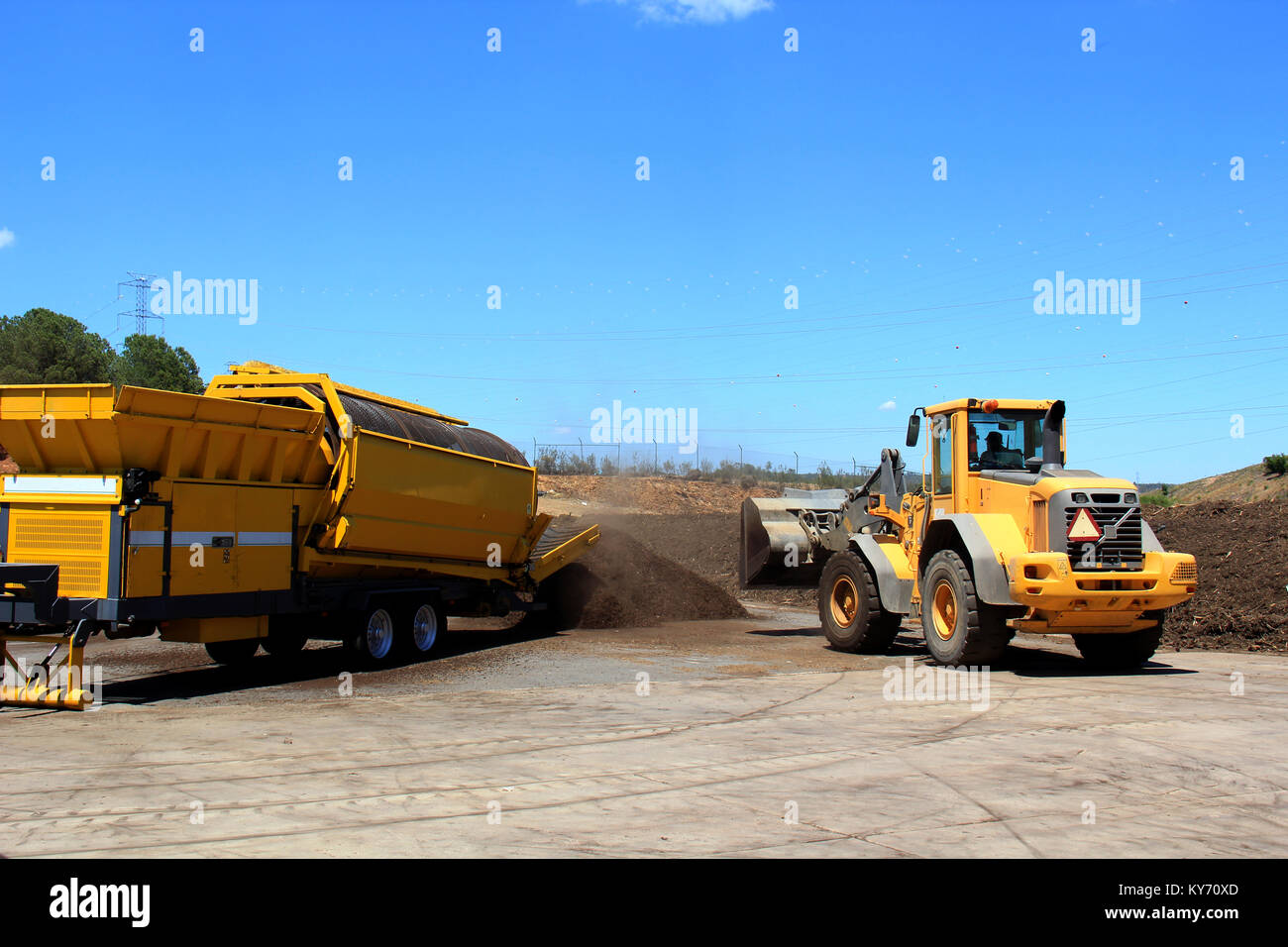 Industrial compost grinder fed by a bulldozer mulching garden waste