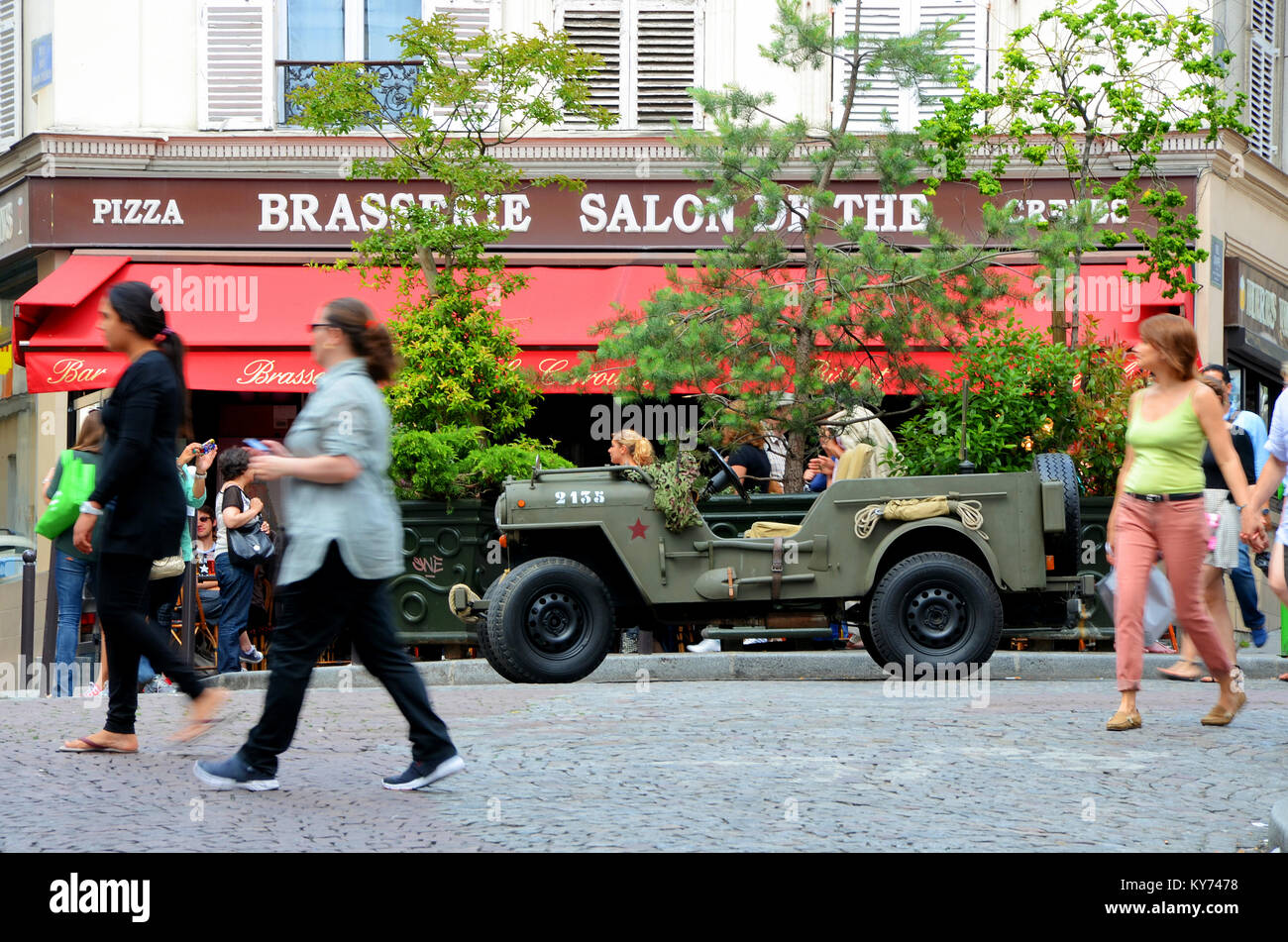 The Salons de thé brasserie in the Montmartre district of Paris, France with wartime American US Jeep outside. People walking by Stock Photo
