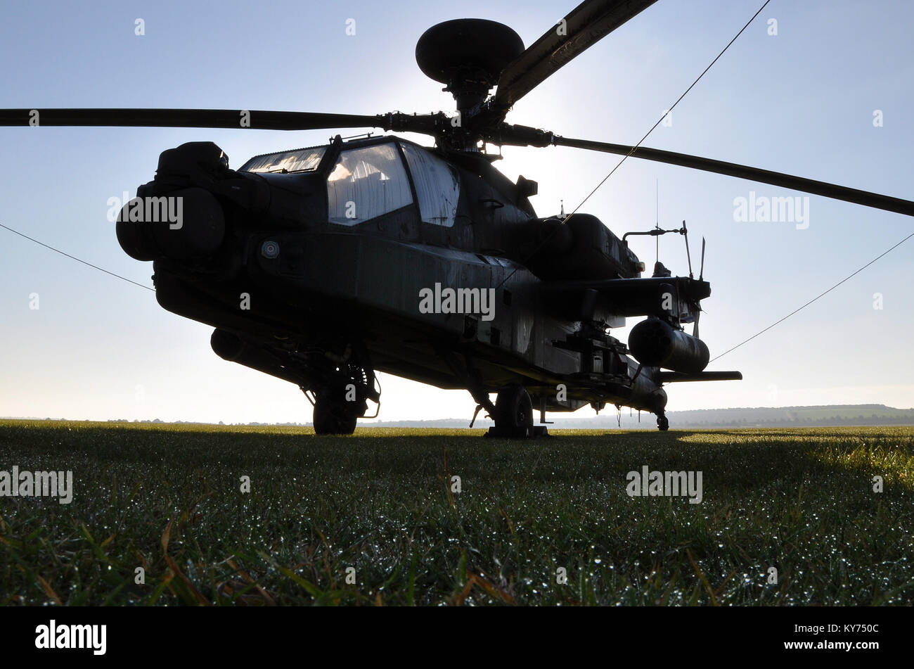 British Army Apache gunship sitting on grass with dew early in the morning. Westland AH-64 Longbow Apache. Space for copy Stock Photo