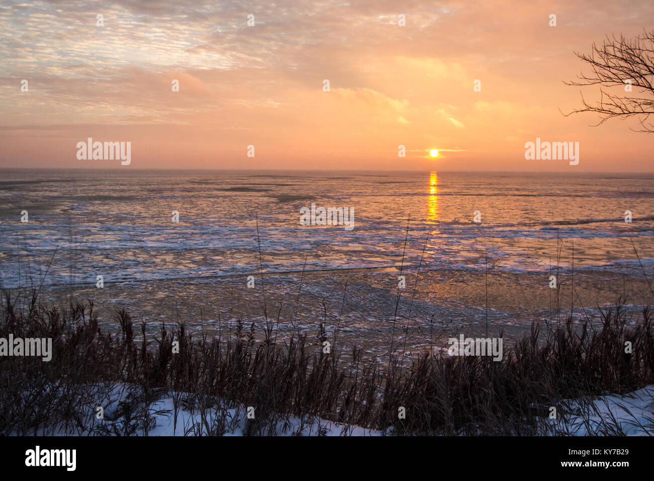 Frozen Winter Sunrise Landscape. Scenic sunrise reflection over the icy Great Lakes horizon on the coast of Lake Huron from an overlook in Port Sanila Stock Photo