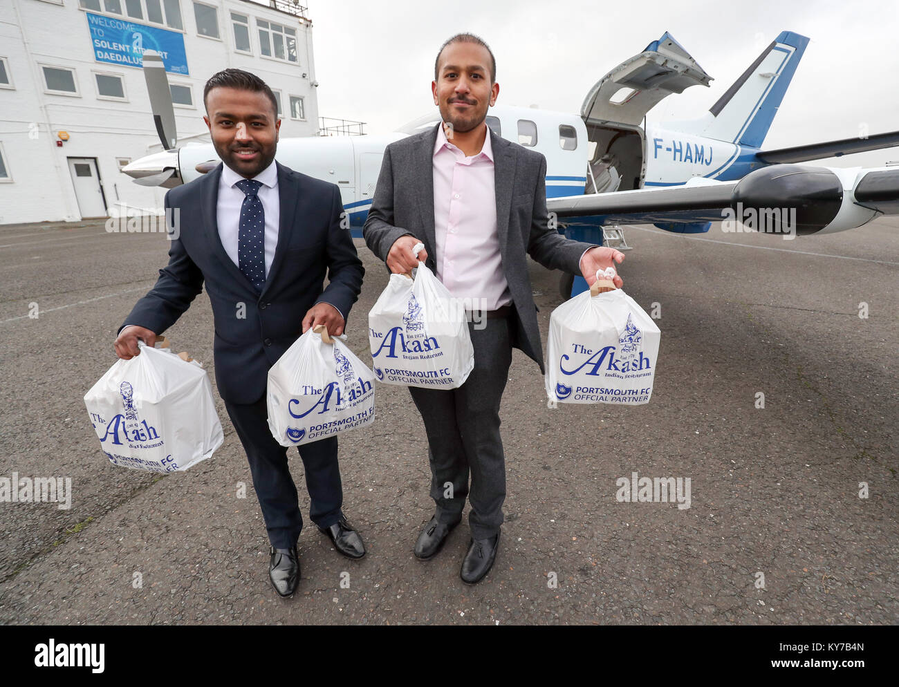 Brothers Faz (right) and Jaf Ahmed from the Akash restaurant in Southsea, Hampshire, load a curry takeaway onto a plane at Solent Airport, Lee-On-The-Solent, so it can be flown to France for British ex-pats James Emery and friends at Saucats Airfield, south of Bordeaux. Stock Photo