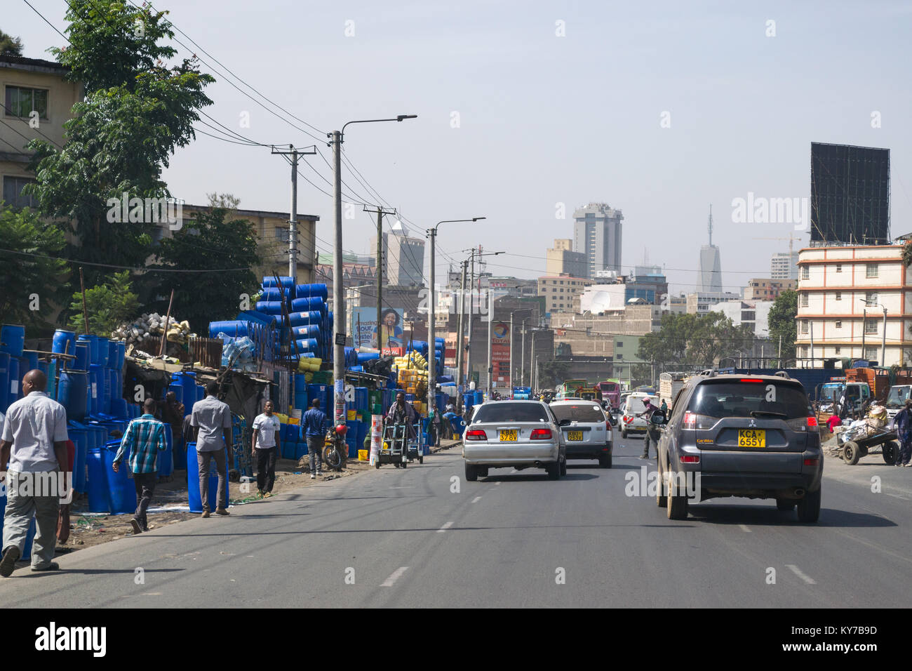Vehicles driving down Ring Road Ngara with stalls and shops on the roadside and people walking, Nairobi, Kenya, East Africa Stock Photo