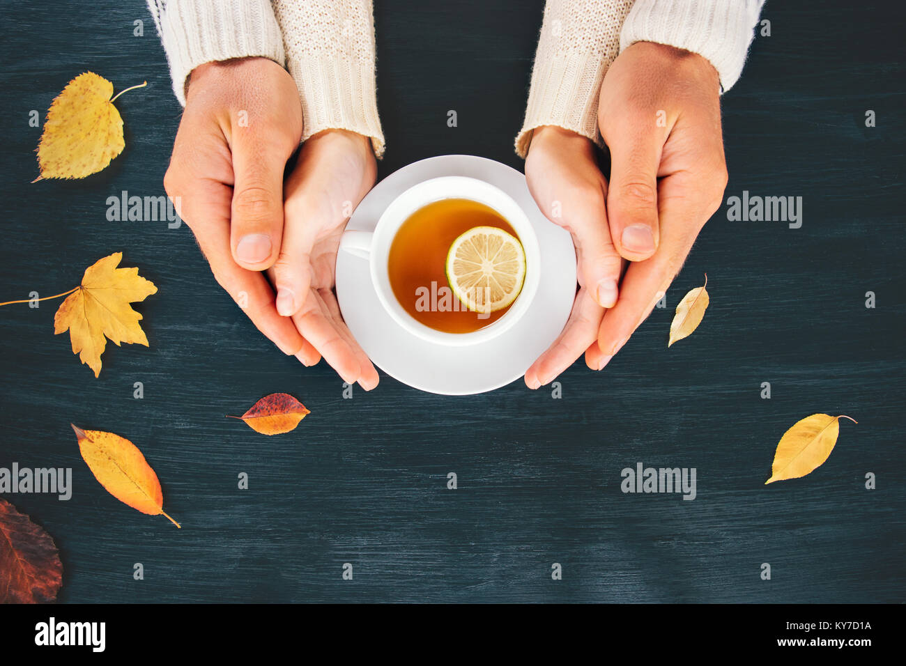 Couple Man and Woman in Love hugging holding hands with hot tea lemon cup on wooden table with autumn leaves Romantic relationship feelings concept to Stock Photo
