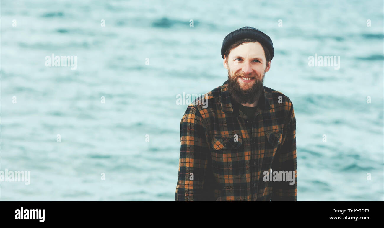 Bearded Man happy smiling walking on sea beach Travel Fashion Lifestyle hat and cozy shirt clothing harmony with nature authentic style concept Stock Photo
